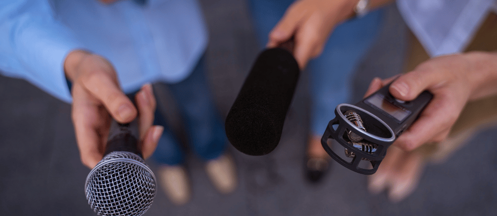 Pessoas segurando microfones ao entrevistar uma pessoa