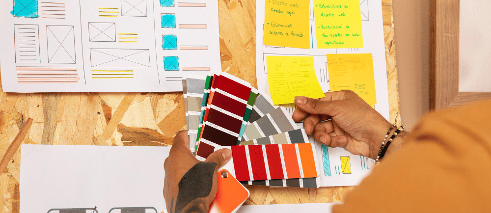 Designer de website com papeís para escolher cores em um mural
