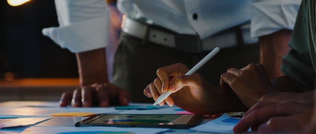 Duas pessoas e mesa com papéis e tablet relacionados a marketing