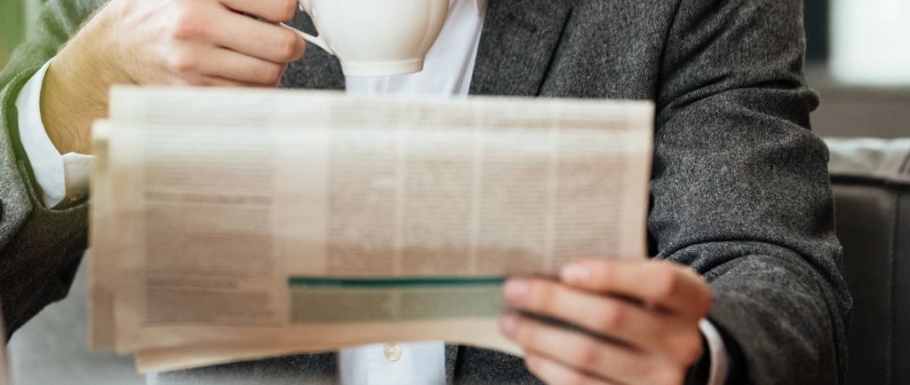 Advogado lendo jornal e tomando café