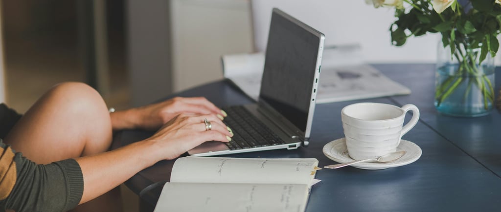 a woman sitting at a table with a notebook and a cup of coffee