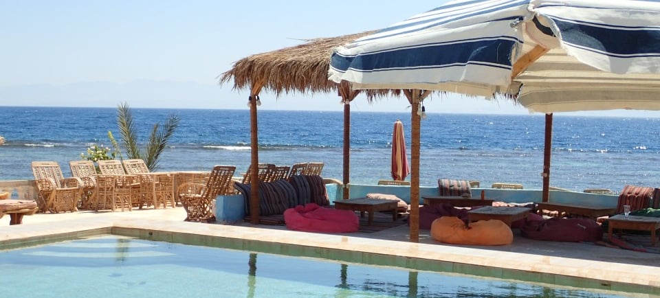 Piscina sulla spiaggia con ombrelloni chaises longues e struttura arisha tradizionale a Bedouin Star