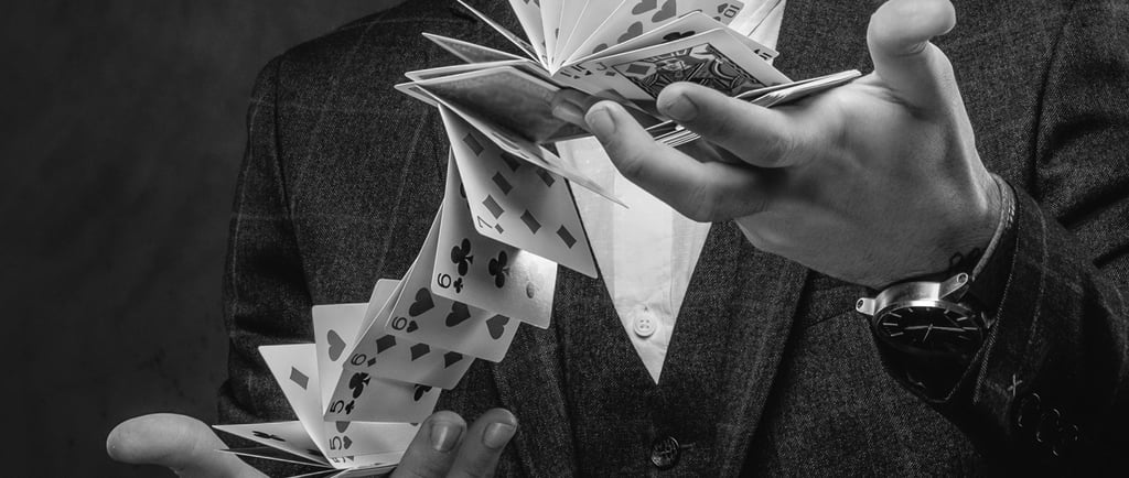 Las manos de un hombre manipulando una baraja en el aire, en gesto de un truco de magia