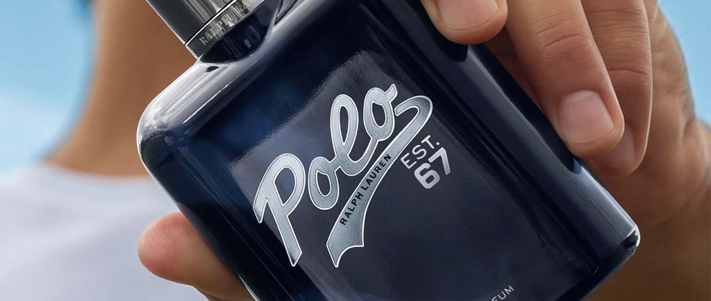 A hand holding a bottle of Ralph Lauren Polo Est. 67 Eau de Parfum men's fragrance against a blue sky.