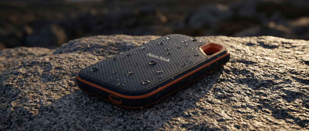 Professional product photography of the SanDisk Extreme Pro V2 SSD on a rugged granite rock. Water d