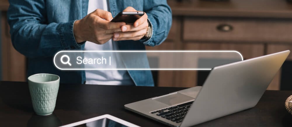 Persona buscando en Google desde móvil y portátil, concepto de SEO en Sabadell