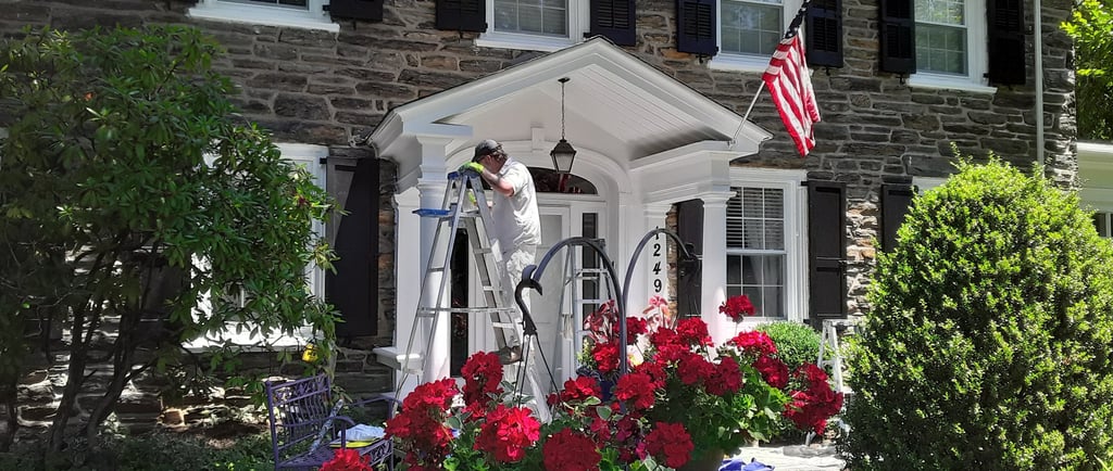 a painter on a ladder painting the front of a house