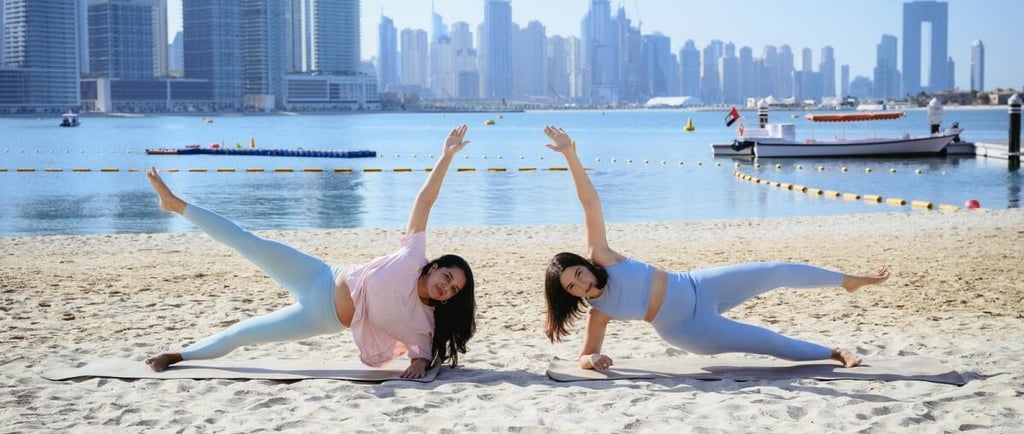 Women practicing online yoga at the beach in dubai