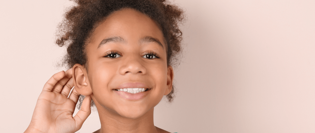 a young girl with a green shirt touching her ear