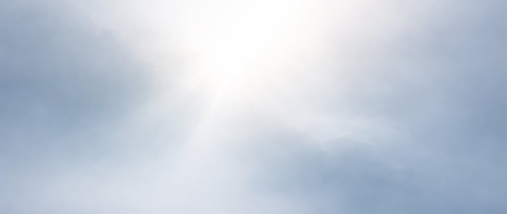 a plane flying through the sky with a sun shining through the clouds