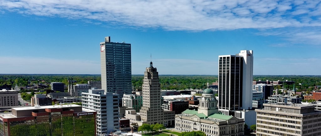 Aerial view of the Fort Wayne skyline featuring the Lincoln Bank Tower and Allen County Courthouse under a blue sky.