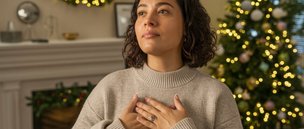 a woman in a sweater holding her hands up to her chest