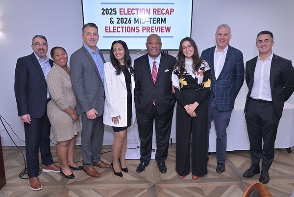 A group of eight professionally dressed people standing together and smiling at a Business Council of Westchester event.
