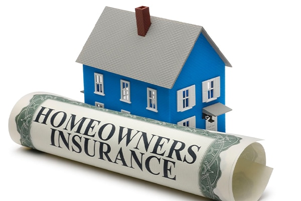 large homeowners policy paper next to a small model home