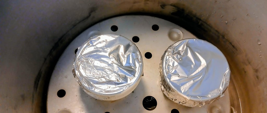 two jars with foil on lids sitting in a pressure cooker