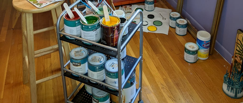 Behr paint cans stacked on an artist's cart in an art studio prepped and mixed for painting a mural.
