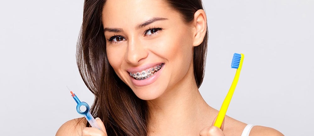 a women wearing bracesand showing toothbrushes in hand