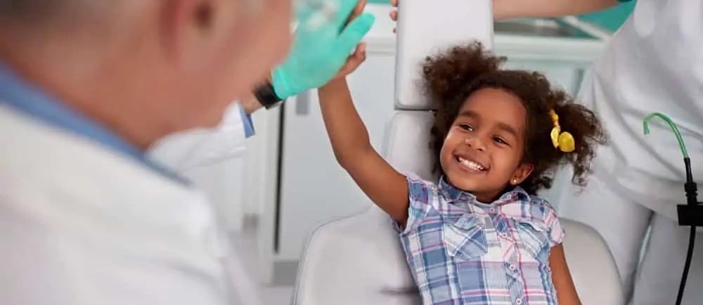 a child beating hands with pediatric dentist