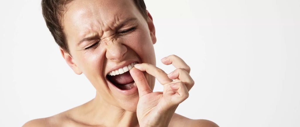 a person trying to remove food stuck between teeth