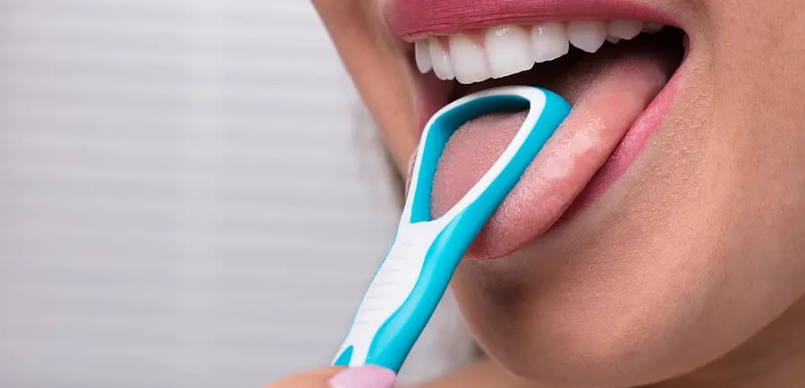 a girl using tongue cleaner in mouth