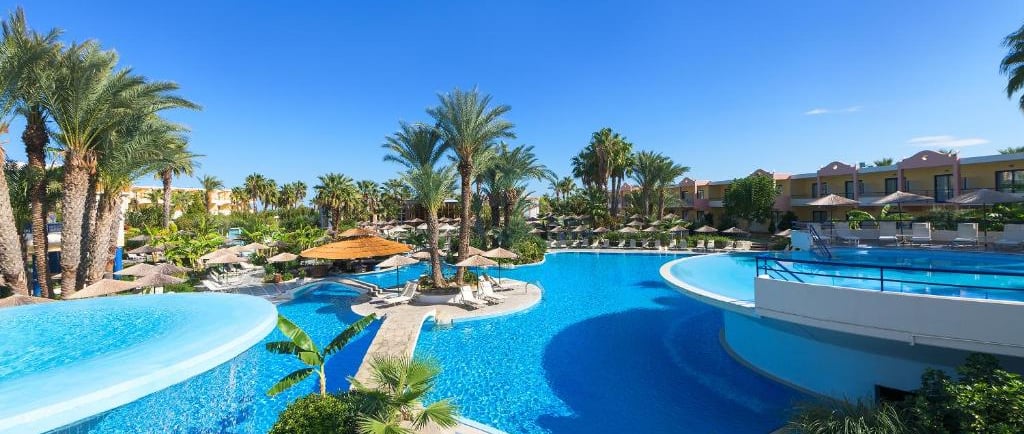 Luxury tropical resort swimming pool with palm trees, blue water, and sun loungers at Atrium Palace 