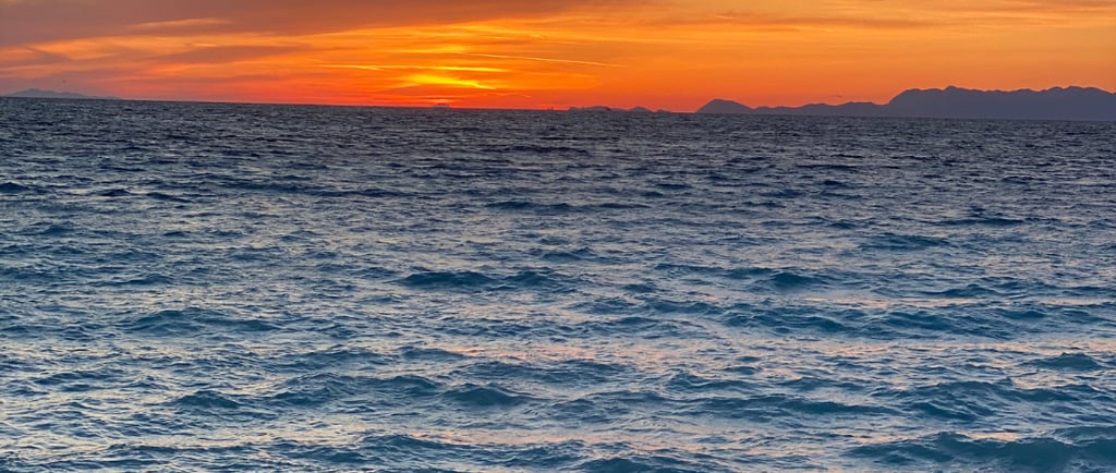 sun is setting behind the blue sea