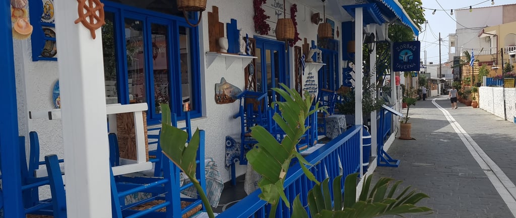 Traditional Greek tavern in Gennadi Rhodes with white walls and blue trim along a cobblestone street