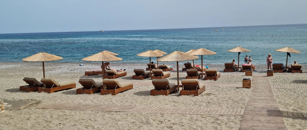Luxury beach resort with straw umbrellas and wooden lounge chairs on a sandy shore by the blue ocean.
