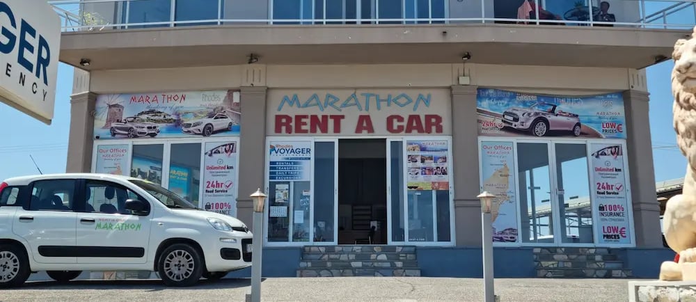 Marathon Rent a Car office building in Rhodes with a white rental car parked out front.