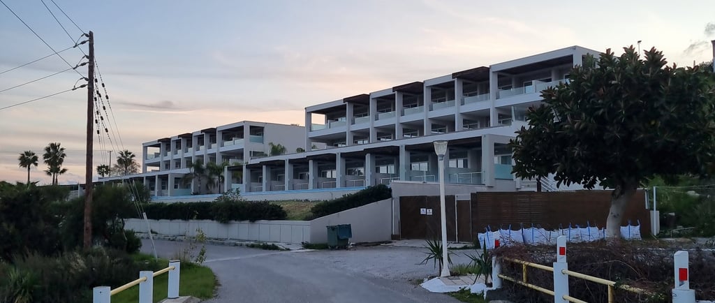 Modern luxury resort apartments with balconies overlooking a paved road at sunset.