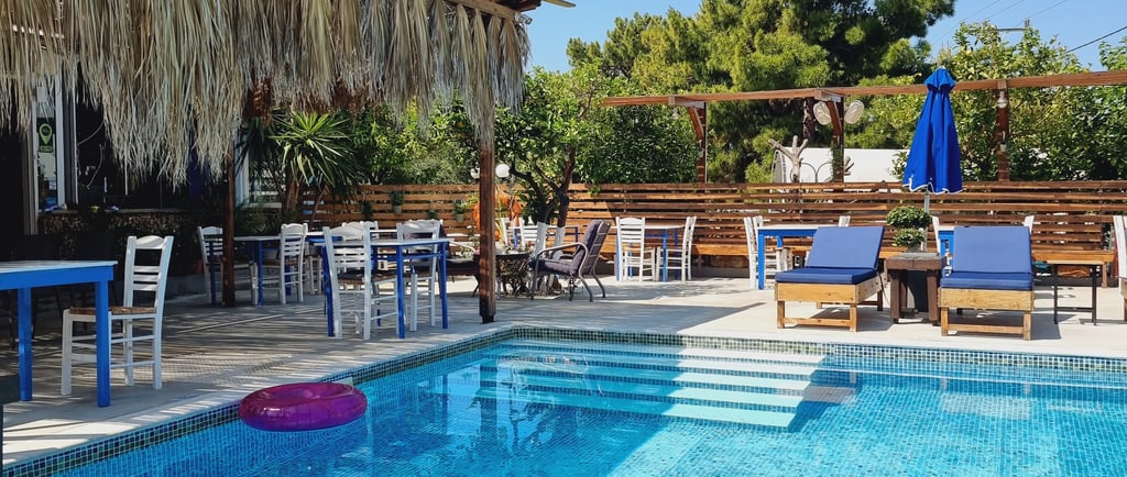 Luxury outdoor resort swimming pool with lounge chairs, dining tables, and a tropical thatched roof.