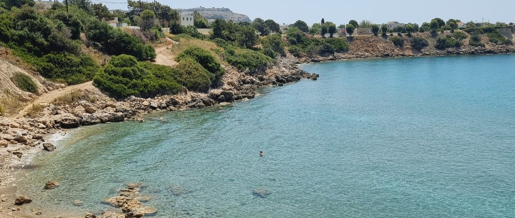 Clear turquoise water and rocky coastline at a Mediterranean beach in Crete, Greece.
