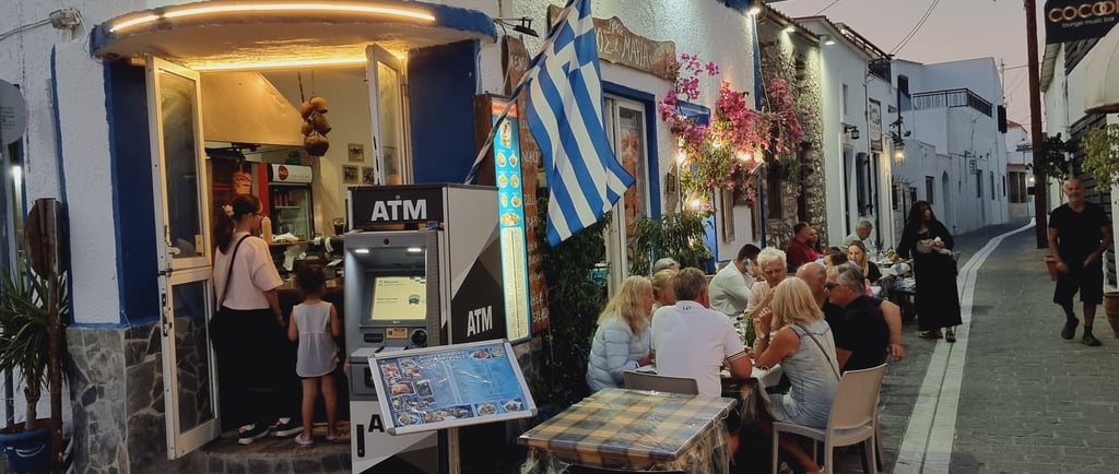 Customers dining outdoors at Nikos and Marias Greek restaurant on a cobblestone street in Naxos.