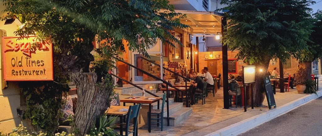 Diners enjoying an evening meal at the Old Times Restaurant outdoor patio under trees.