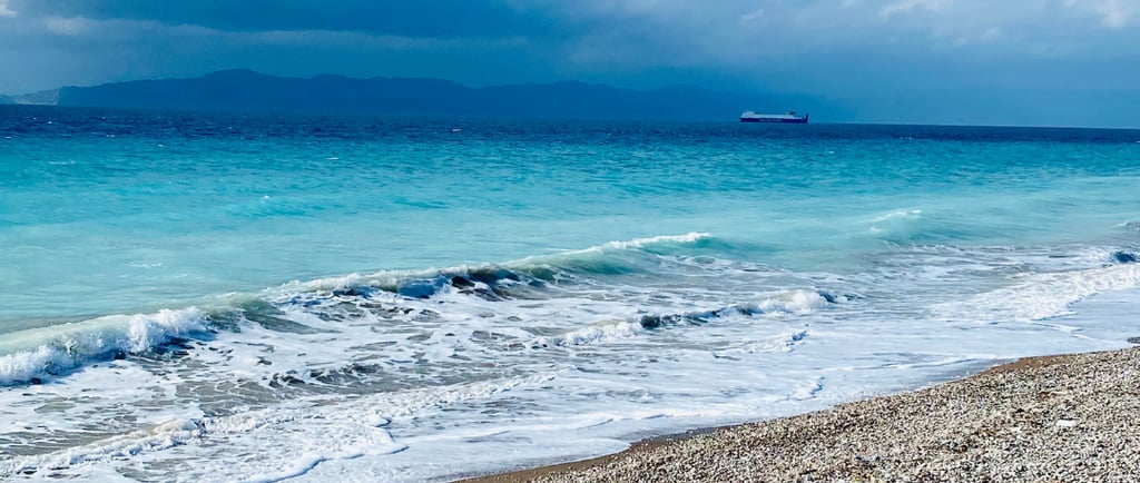 blue sea with some pebbles and waves
