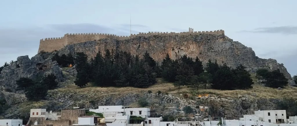Panoramic view of the Acropolis of Lindos above white houses in Rhodes, Greece.