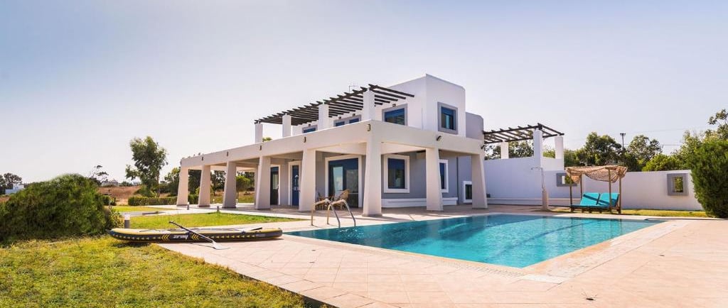 Luxury white vacation villa with a private outdoor swimming pool and sunny garden terrace.