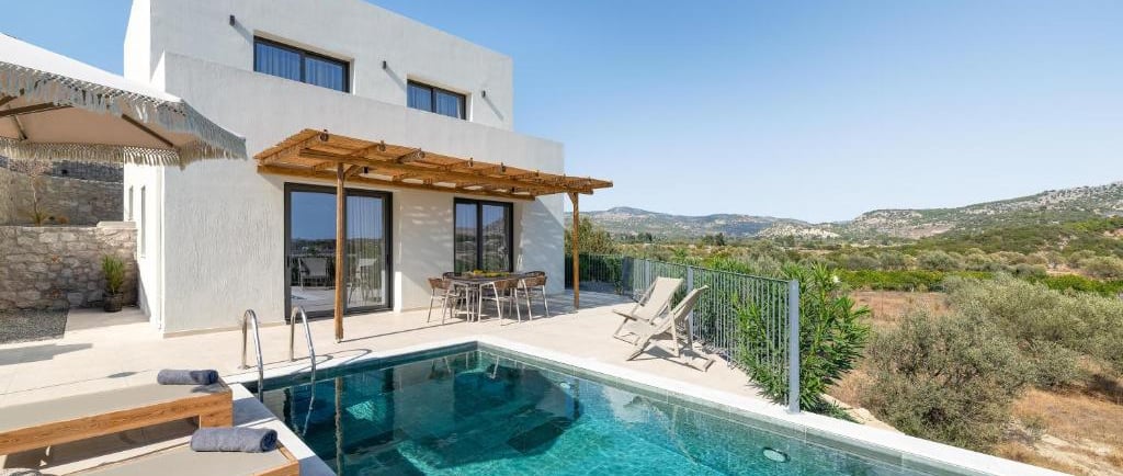Luxury modern villa with a private infinity pool and sun loungers overlooking a scenic Greek valley.