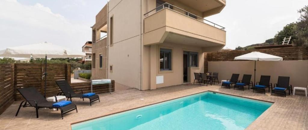 Luxury modern villa with private outdoor swimming pool and sun loungers for a relaxing vacation.