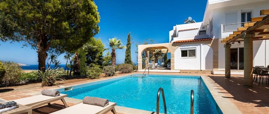 Luxury white villa with private swimming pool and ocean view terrace in a tropical garden.