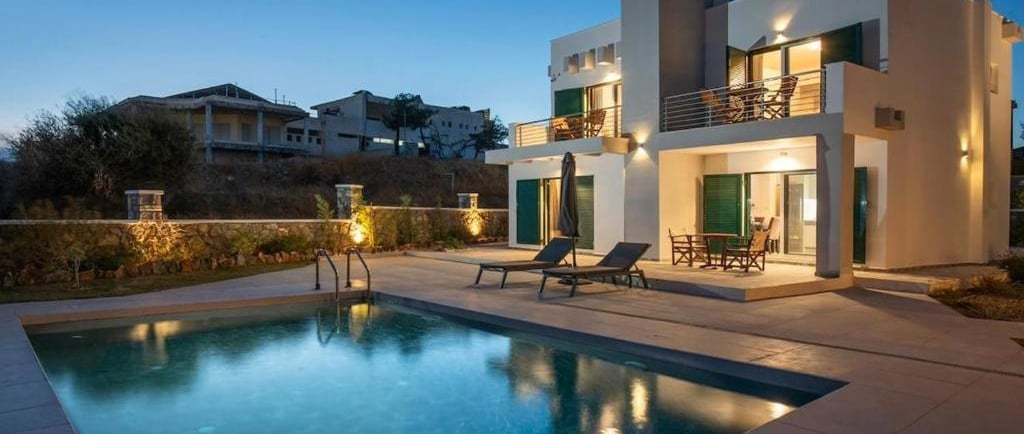 Luxury modern villa with private swimming pool and outdoor patio furniture at twilight.