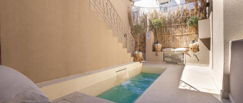 Luxury private plunge pool in a modern Mediterranean courtyard with stone tile and bamboo accents.