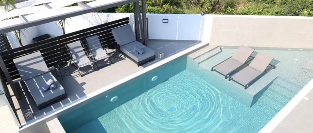 Luxury modern villa patio with private swimming pool, sun loungers, and pergola.