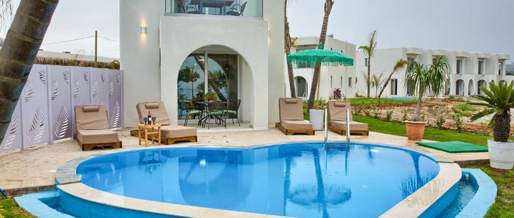 Luxury vacation villa with heart-shaped swimming pool and modern poolside lounge area.