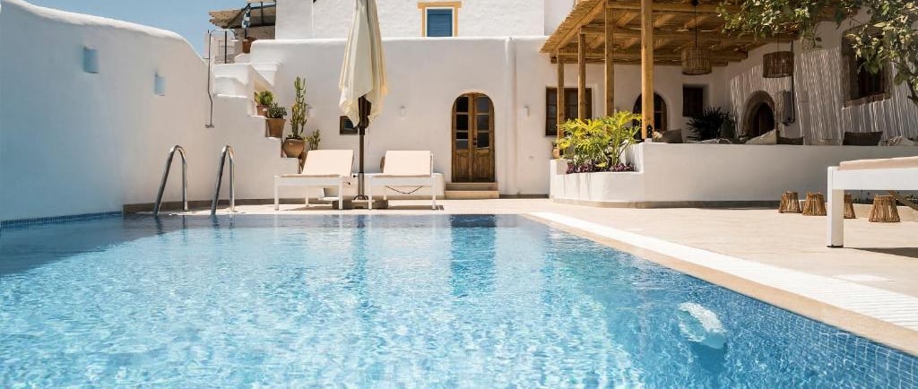 Luxury Greek villa with a private turquoise swimming pool, white architecture, and sun loungers.