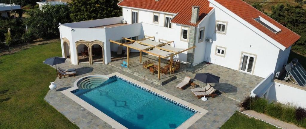 Luxury white villa with red tile roof and private swimming pool overlooking the Mediterranean sea.