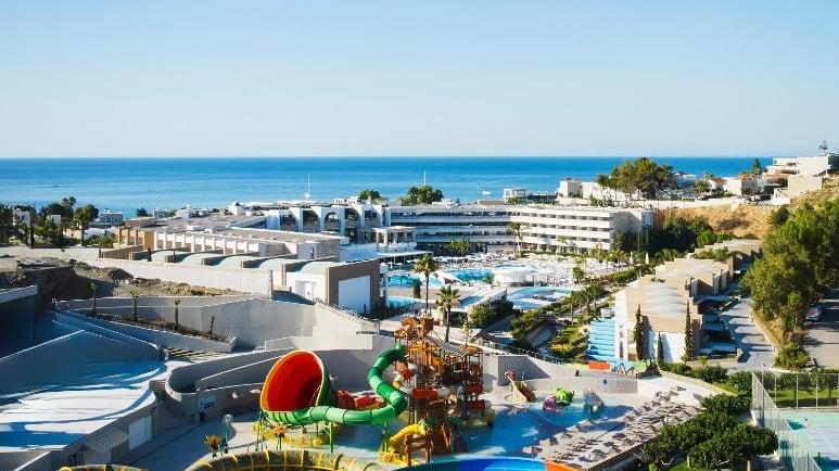 Luxury beach resort with a vibrant water park and colorful water slides overlooking the blue ocean.