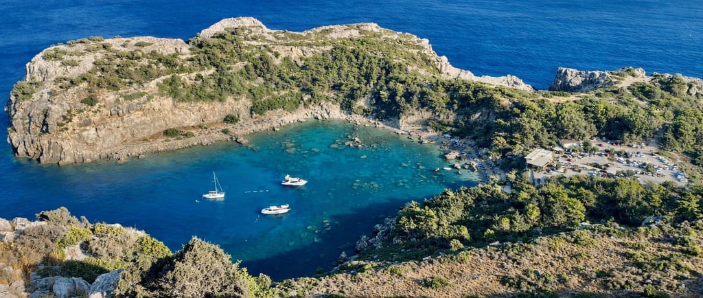 Aerial view of Anthony Quinn Bay in Rhodes, Greece, with yachts anchored in turquoise Mediterranean waters.