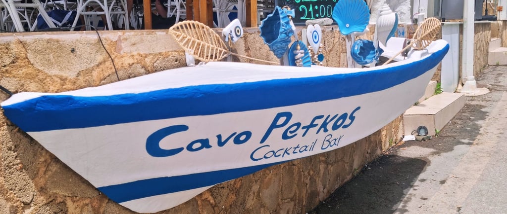 Cavo Pefkos Cocktail Bar entrance in Rhodes, Greece featuring a blue and white decorative boat sign.