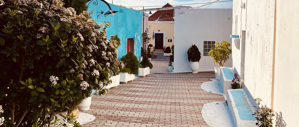 a brick walkway with a bench colorful houses in rhodes